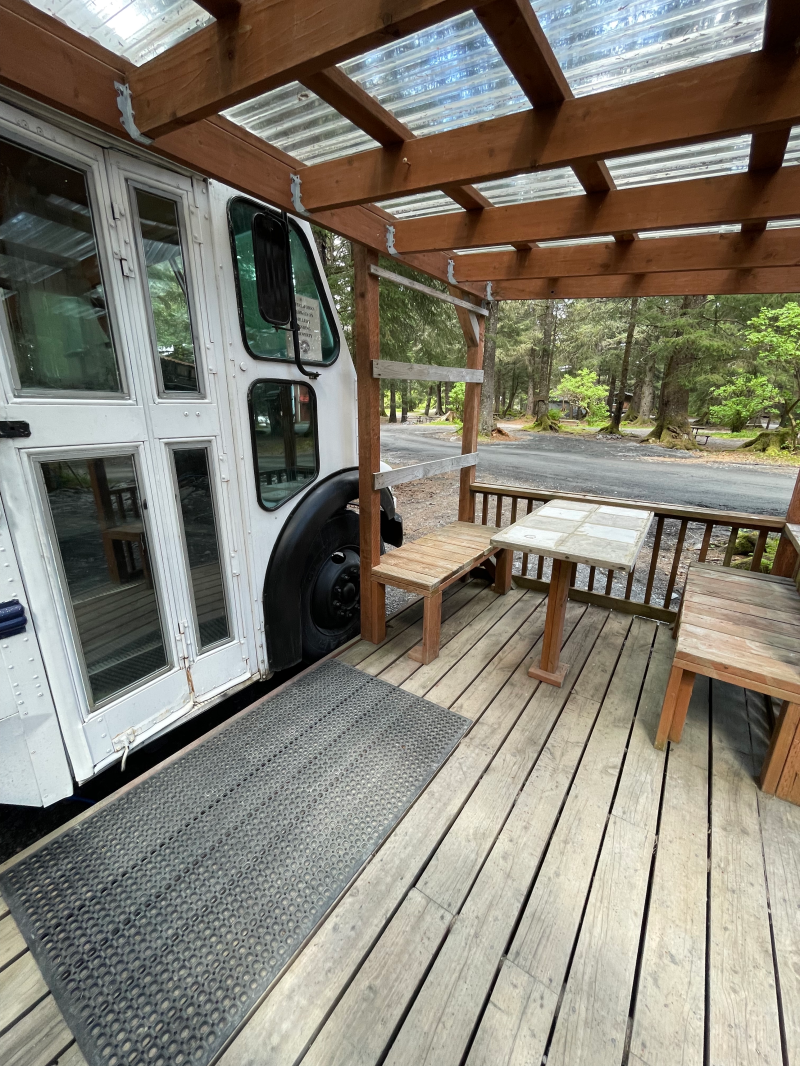 entrance of the magic bus with a picnic table on the covered porch