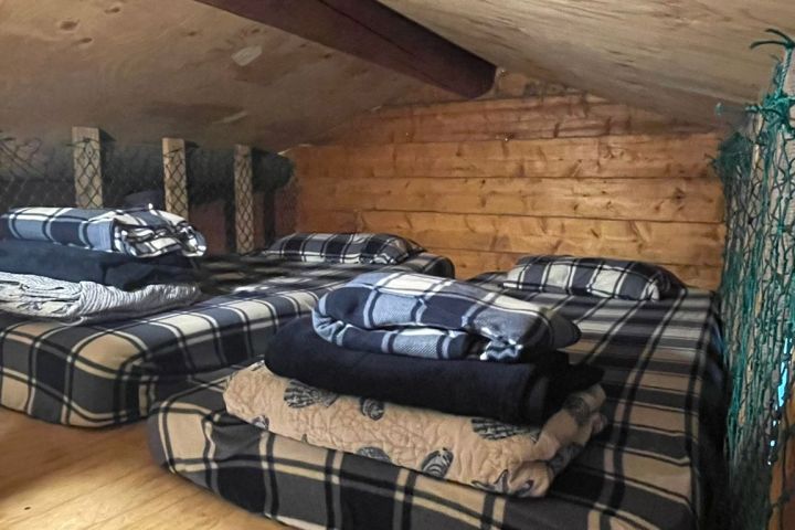 Small loft space with three plaid-covered mattresses and folded blankets.