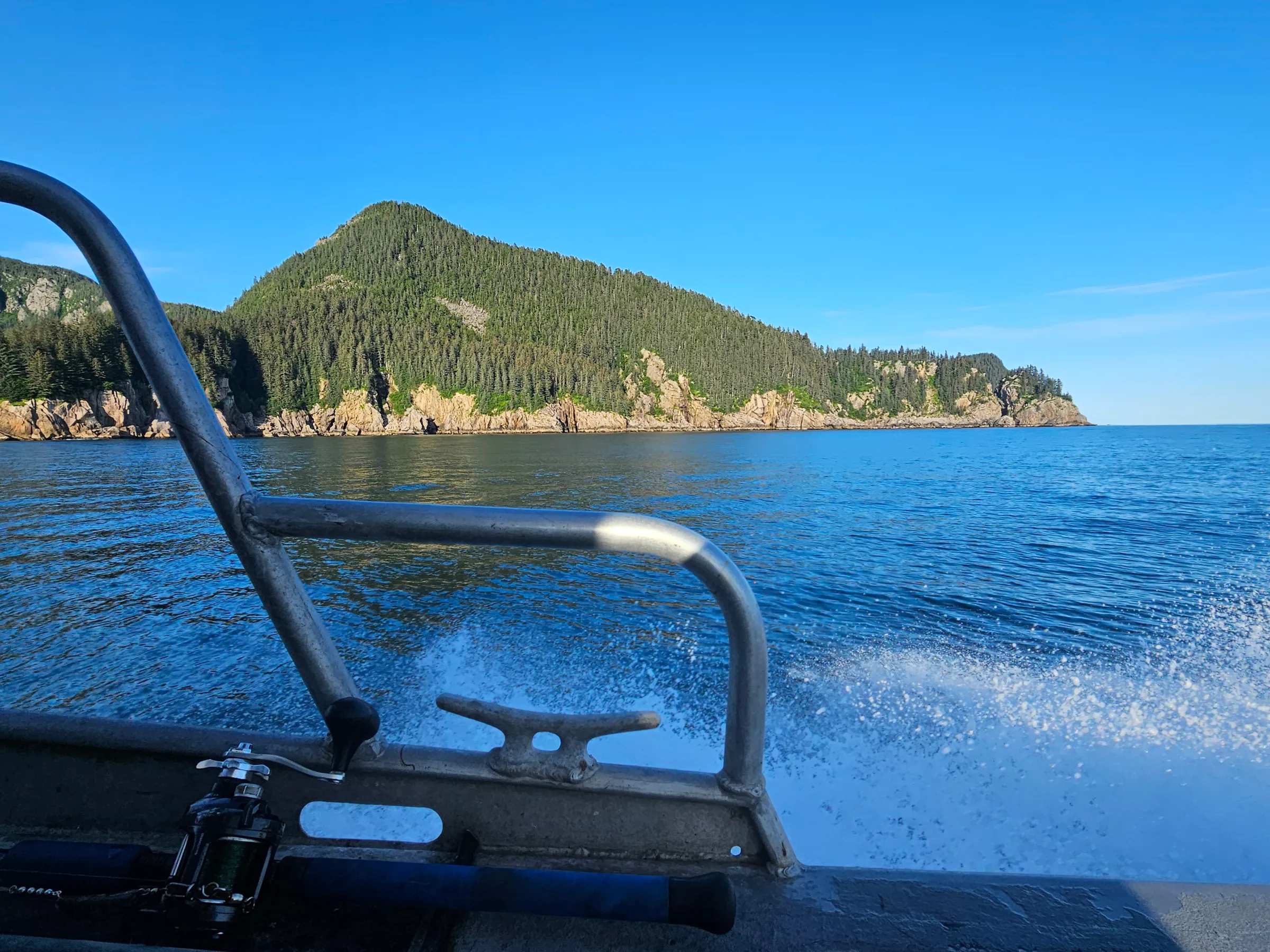 View from a boat with surrounding mountains and clear blue sky.
