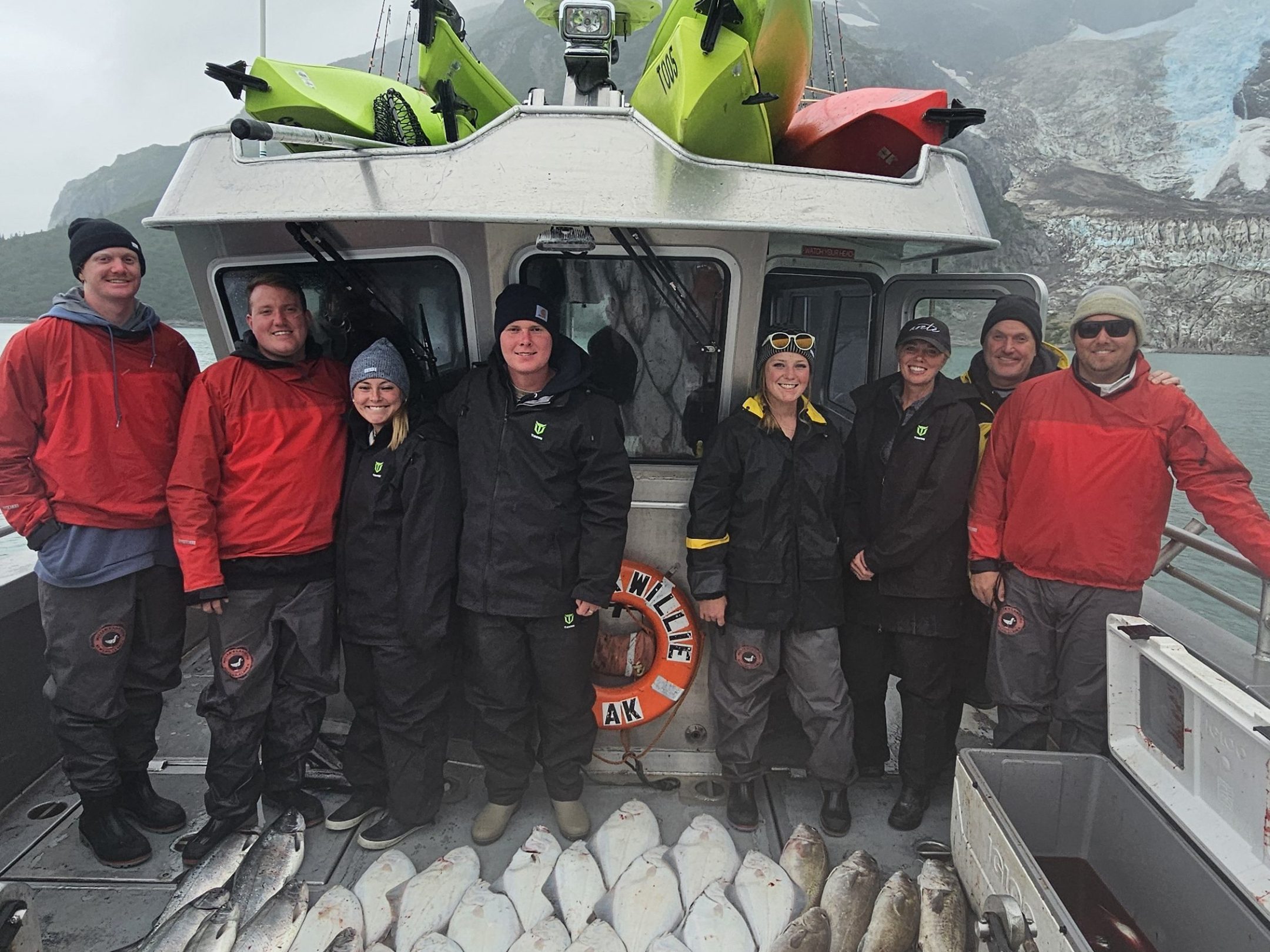 Group of people on a fishing boat with a large catch of fish on the deck.