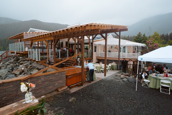Outdoor gathering with tables, pavilion, and mountain backdrop on a cloudy day.