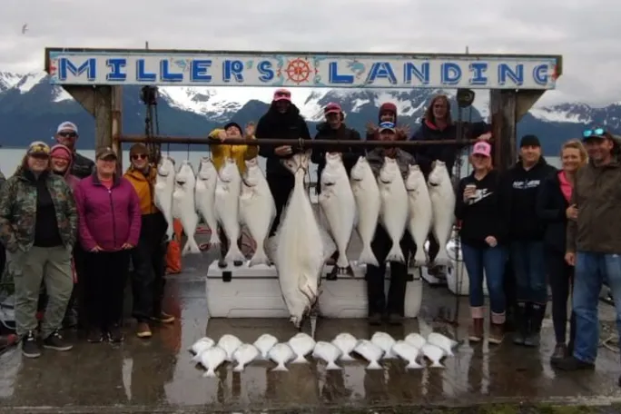 Group with fish catch at Miller's Landing by a scenic water and mountain view.