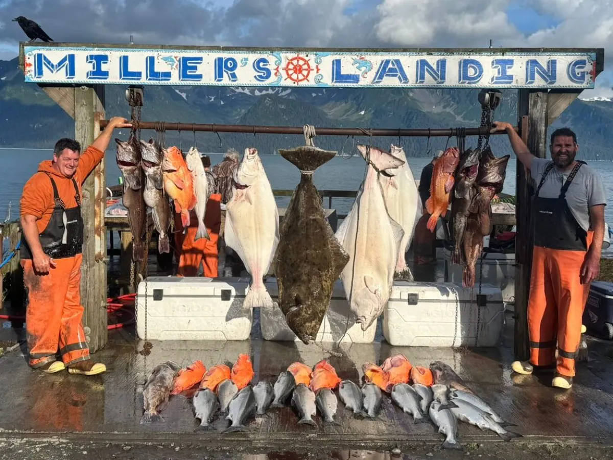 Fishermen display a large catch of fish at Miller's Landing by a scenic lake and mountain background.