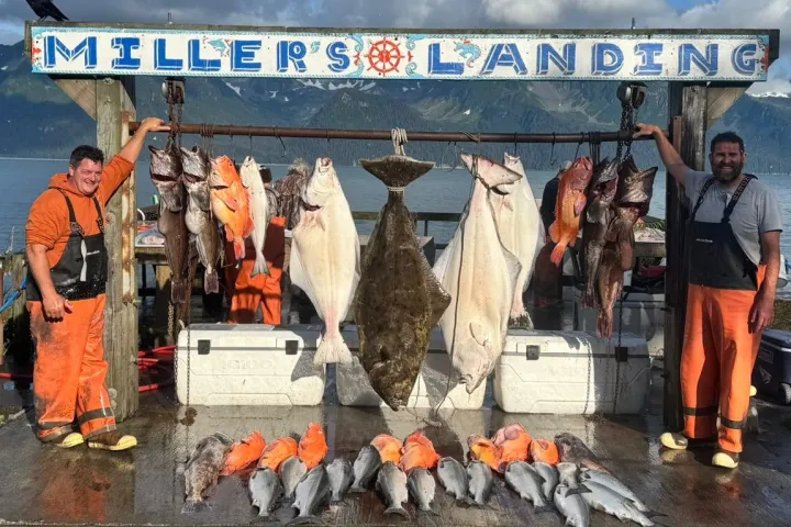 Fishermen display a large catch of fish at Miller's Landing by a scenic lake and mountain background.