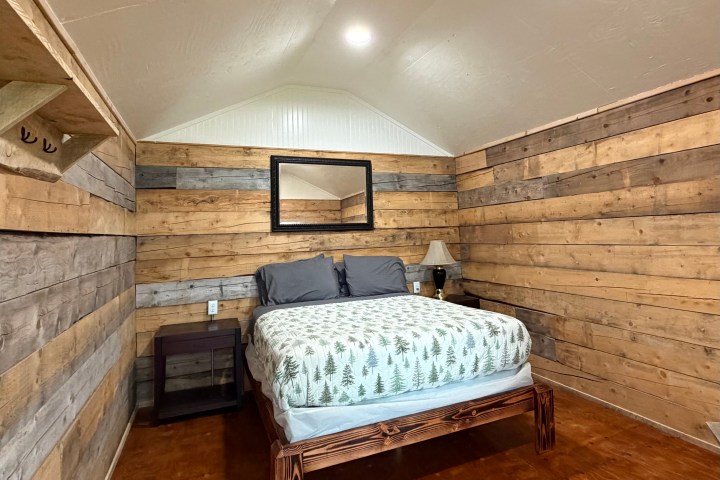 Wood-paneled bedroom with bed, nightstand, and mirror.