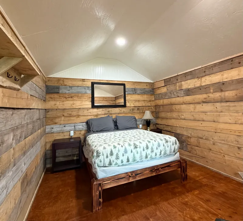 Wood-paneled bedroom with bed, nightstand, and mirror.